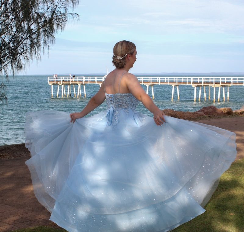 a woman in a blue and white dress is walking by the water