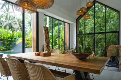 A dining room with a large wooden table surrounded by chairs