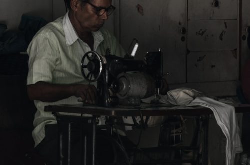 man sitting on chair working on sewing machine