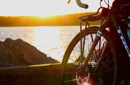 black bicycle near body of water during sunset